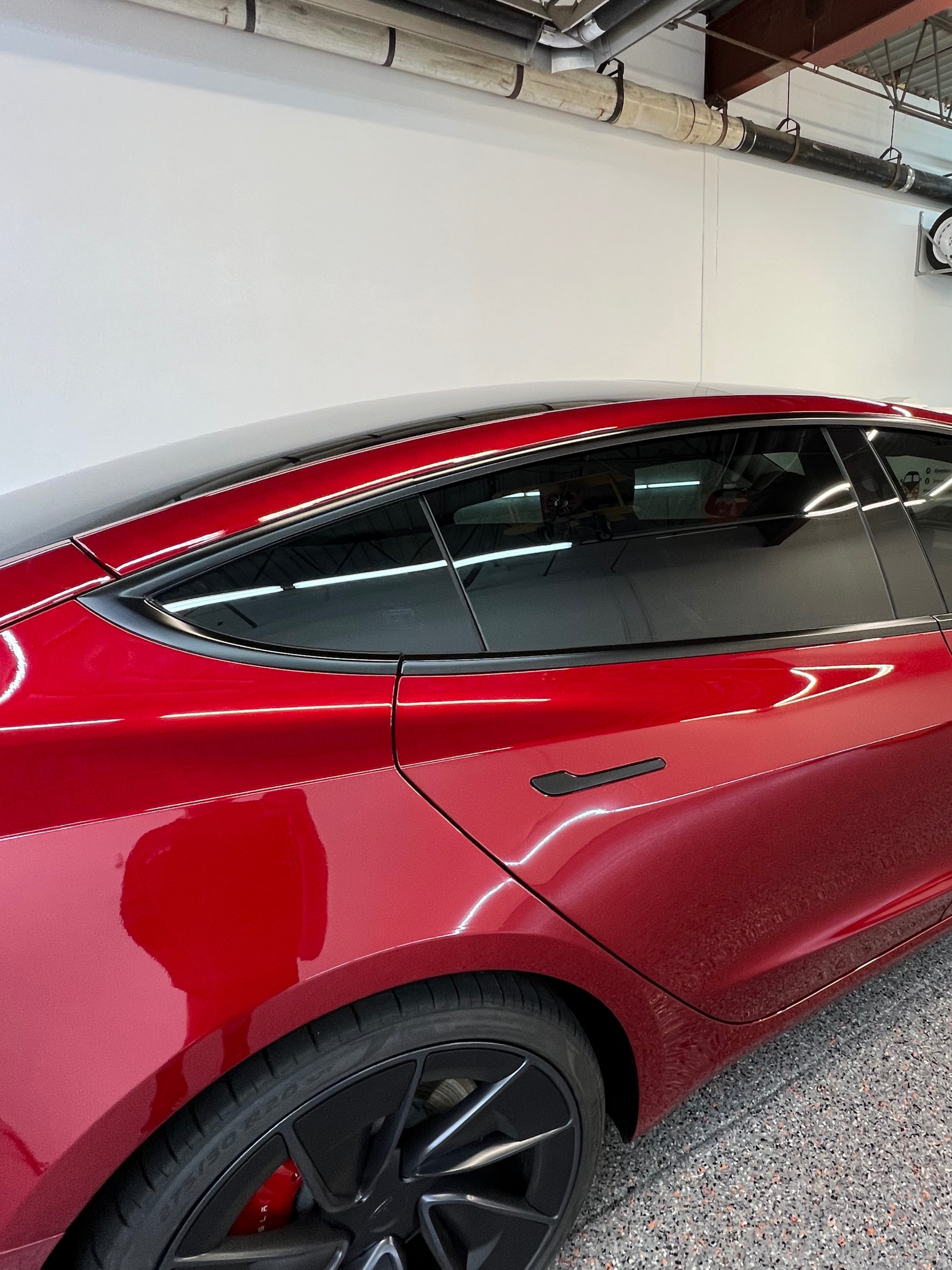 A red tesla model 3 is parked in a garage