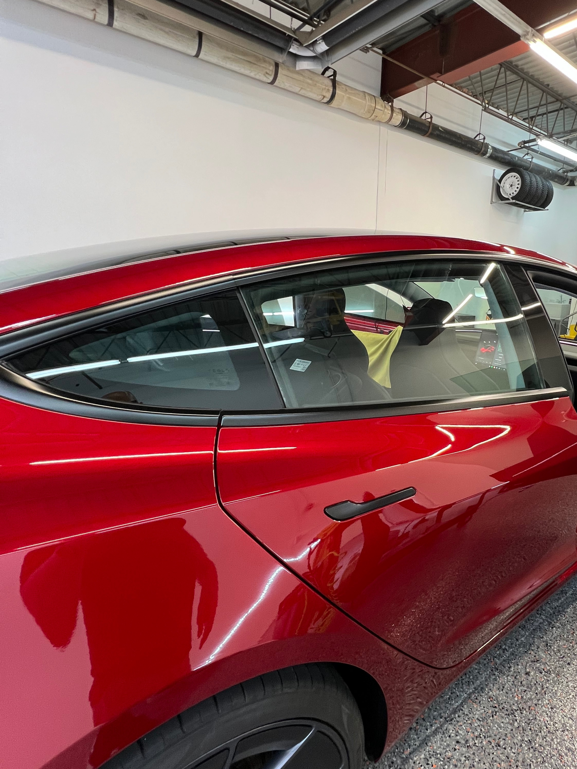 A red tesla model 3 is parked in a garage.