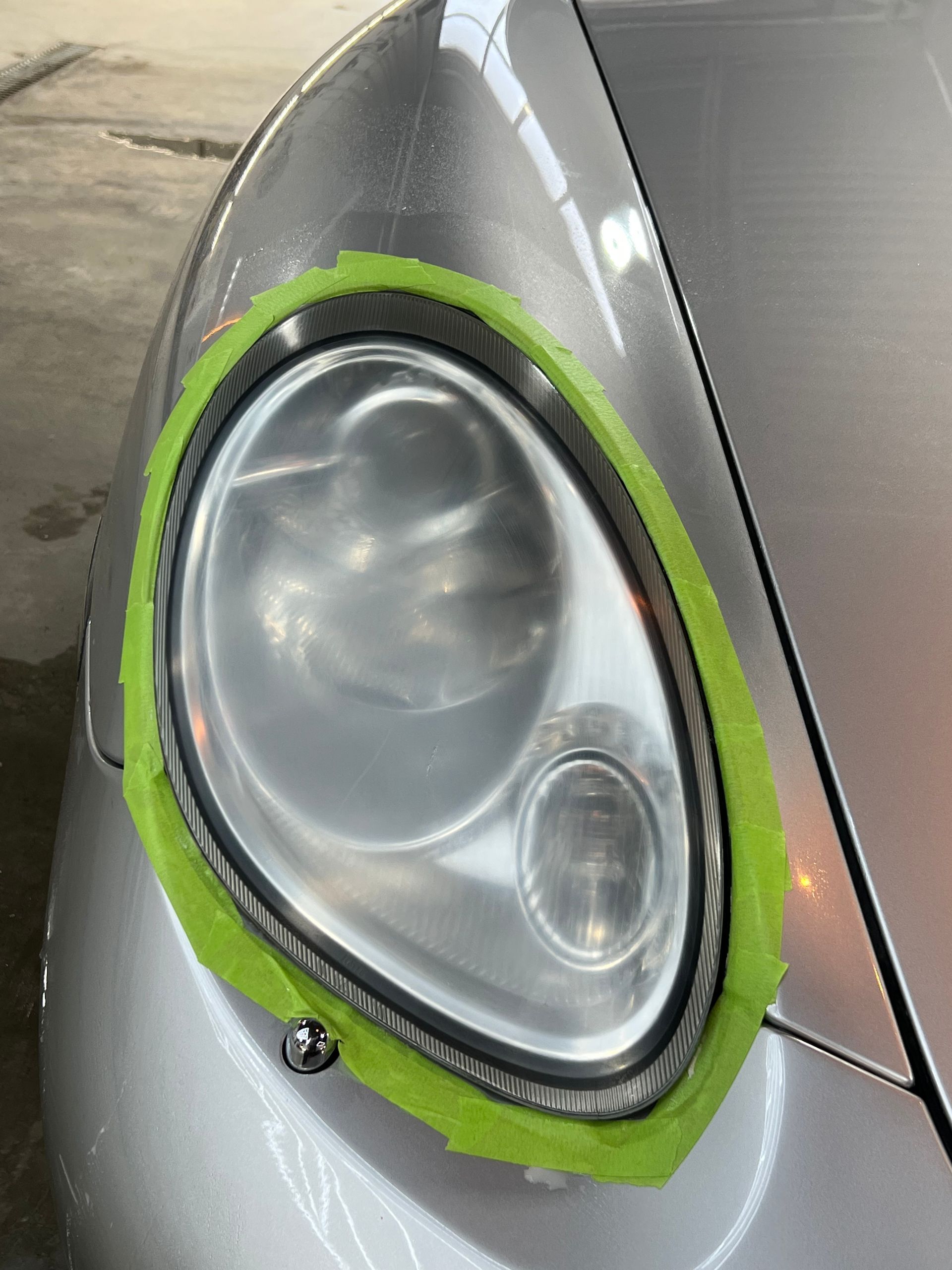 A close up of a car headlight with green tape around it.