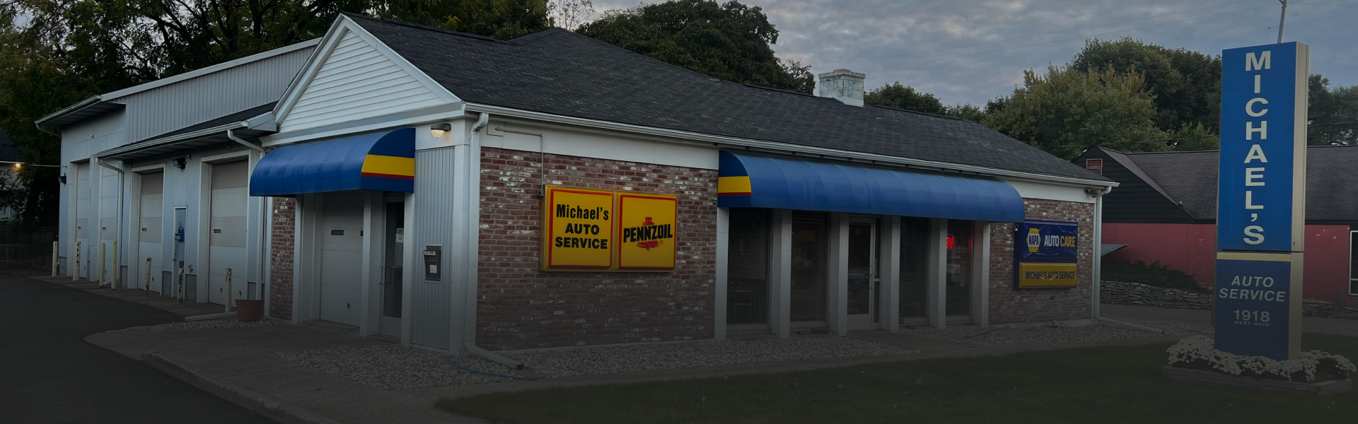 Exterior of Michael's restaurant. Blue awnings, a signpost, and a brick facade are visible. | Michael's Auto Service