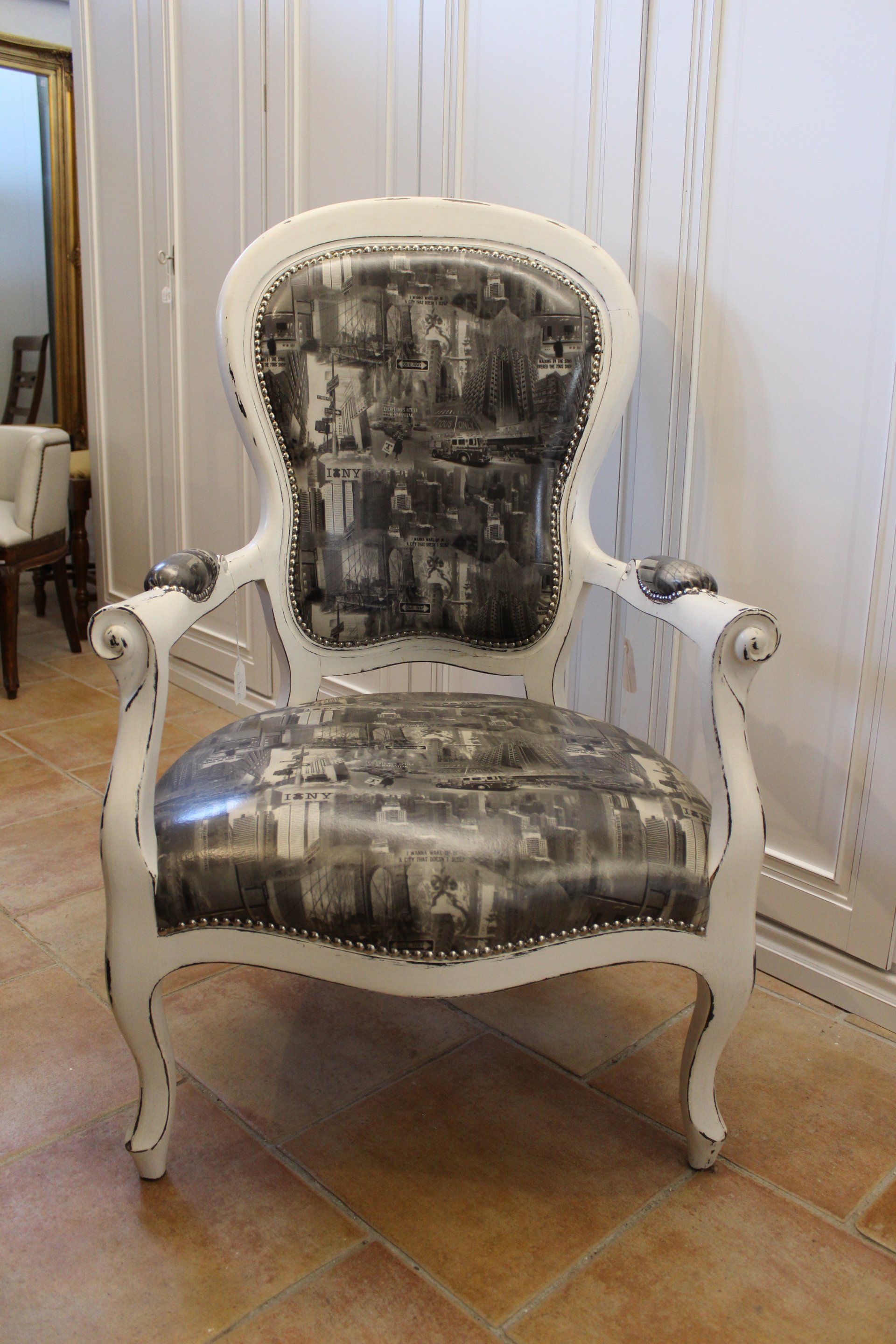 Sedia antica bianca con rivestimento raffigurante una scena cittadina in bianco e nero.