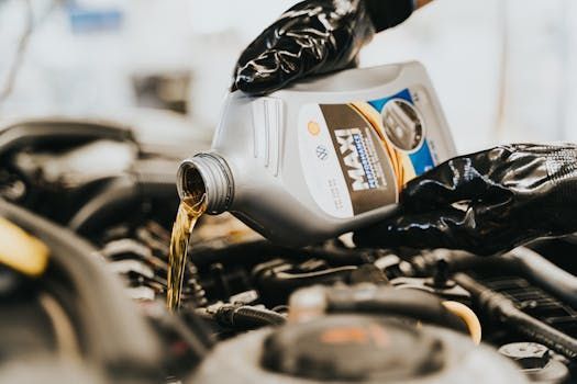 Person in gloves pouring motor oil into a car engine.