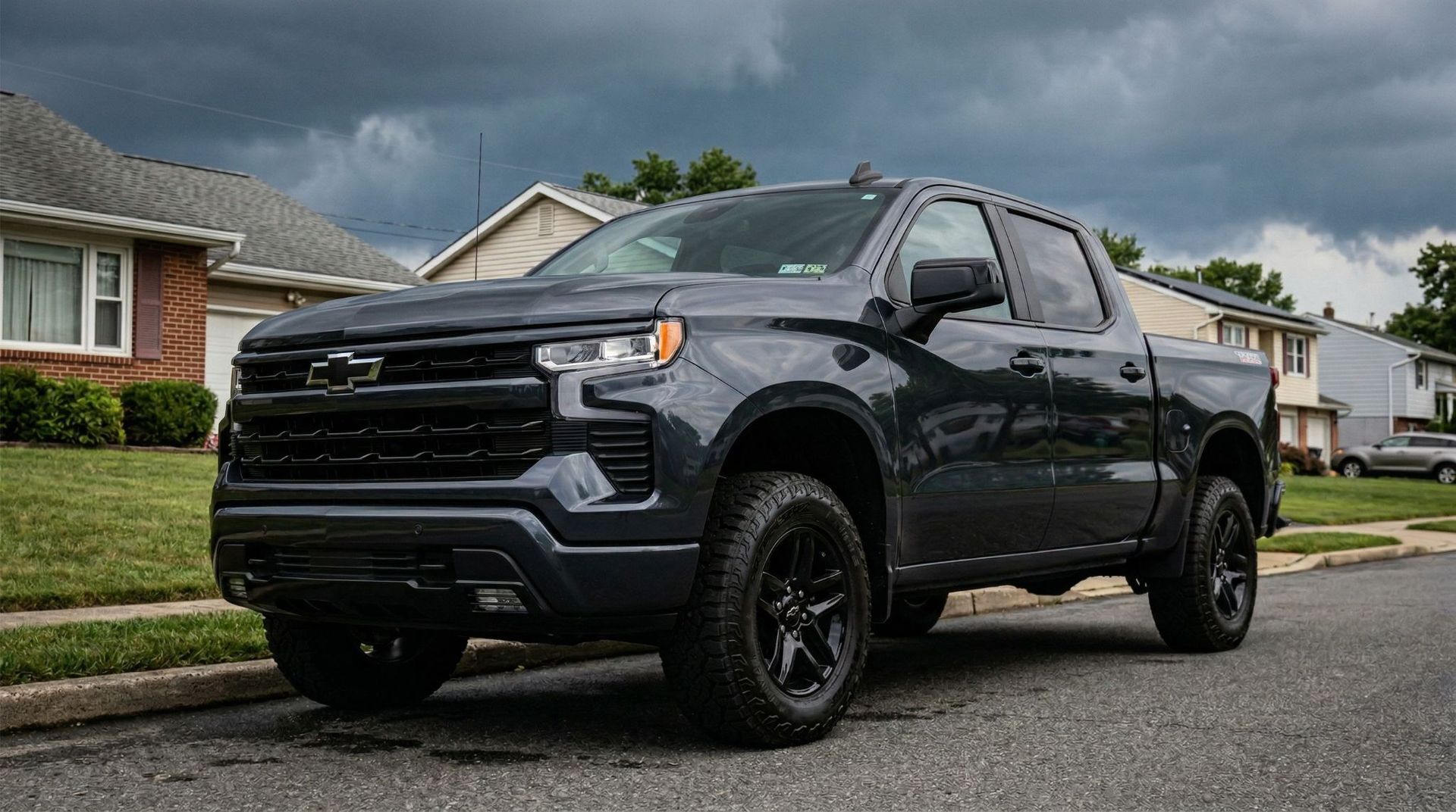 A dark gray Chevrolet Silverado pickup truck parked on a suburban street under a cloudy sky.