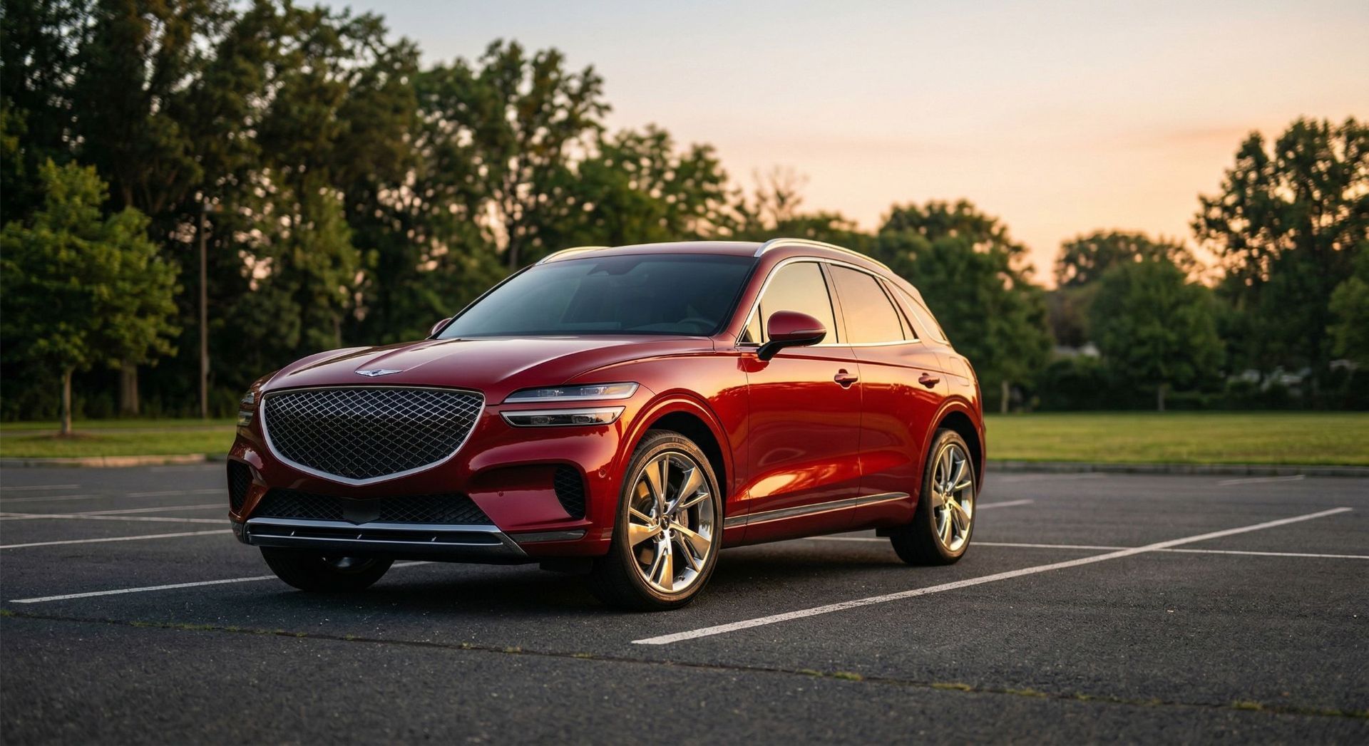 A deep red Genesis GV70 SUV parked in an asphalt lot during sunset with green trees in the background.