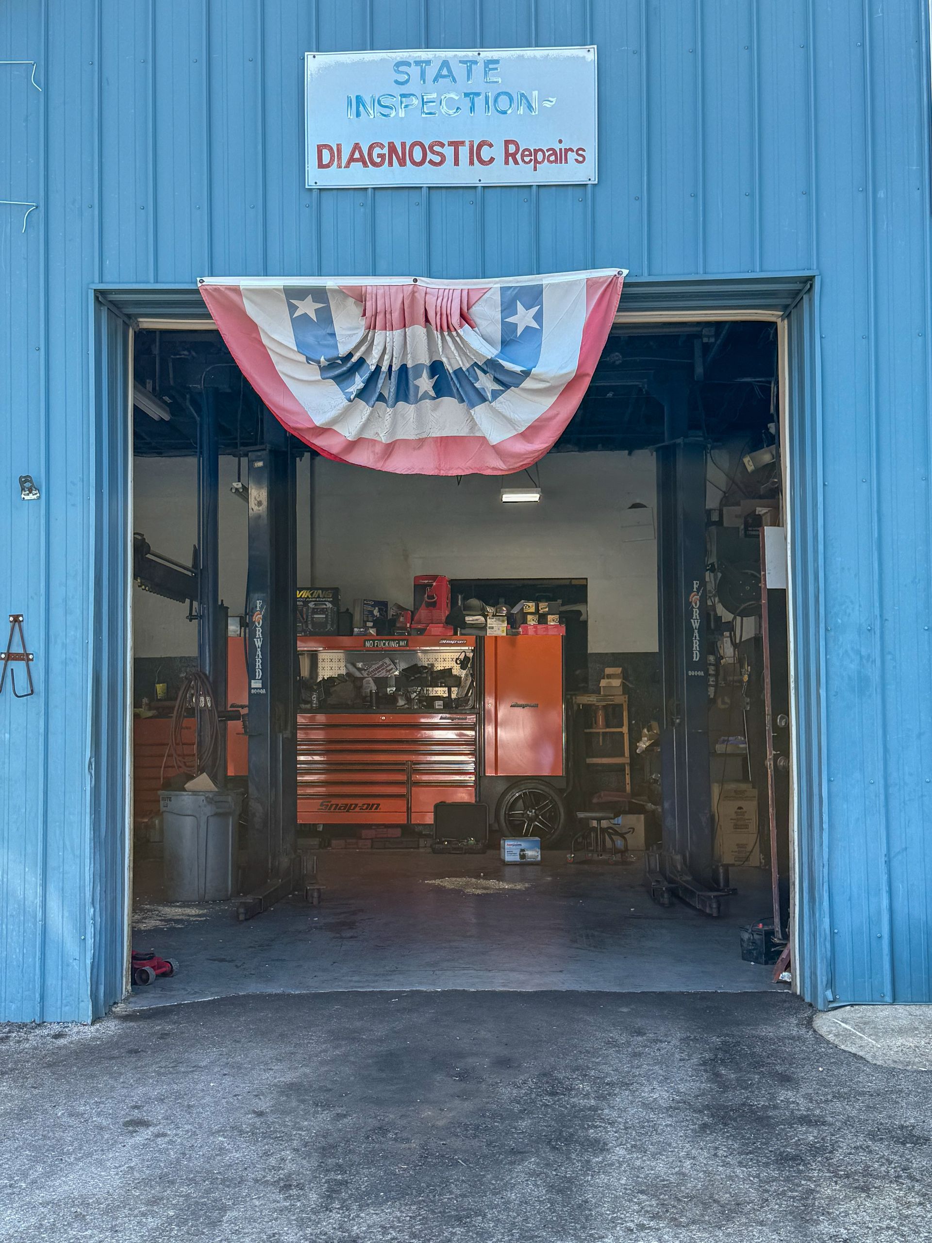 S&S Automotive Service shop interior with a car on a lift, tools, and equipment.