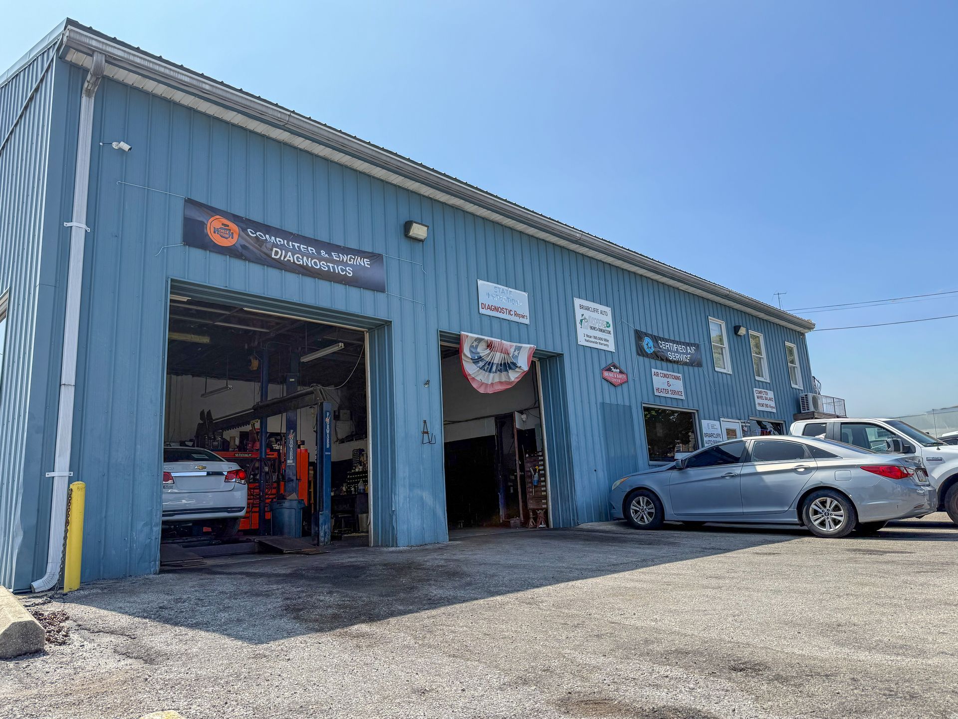 Briarcliffe Auto Service's blue auto repair shop with open bays, cars, and signage.