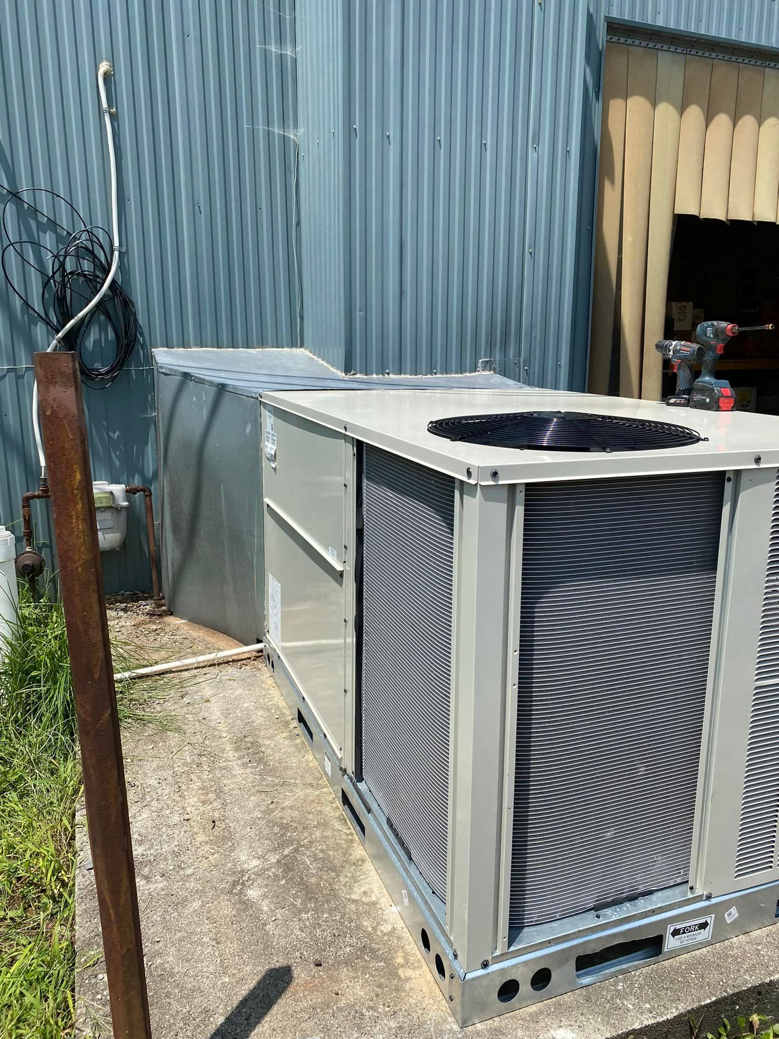 A large air conditioner is sitting outside of a building.