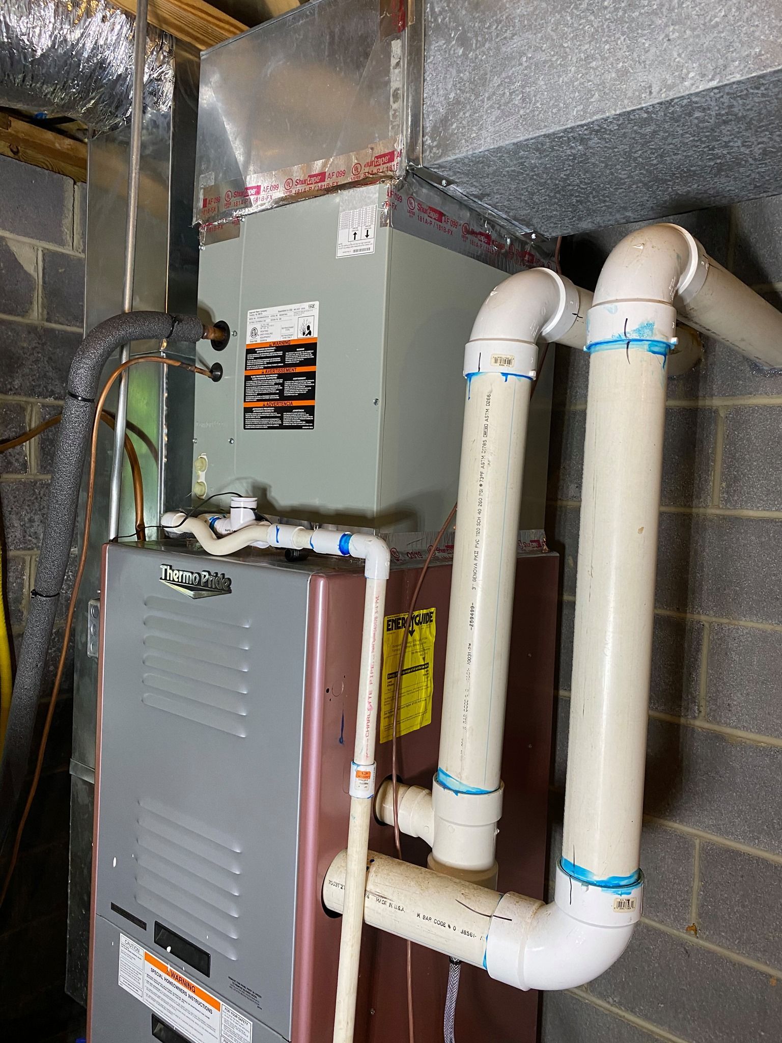 An air conditioner is sitting in a basement next to a brick wall.