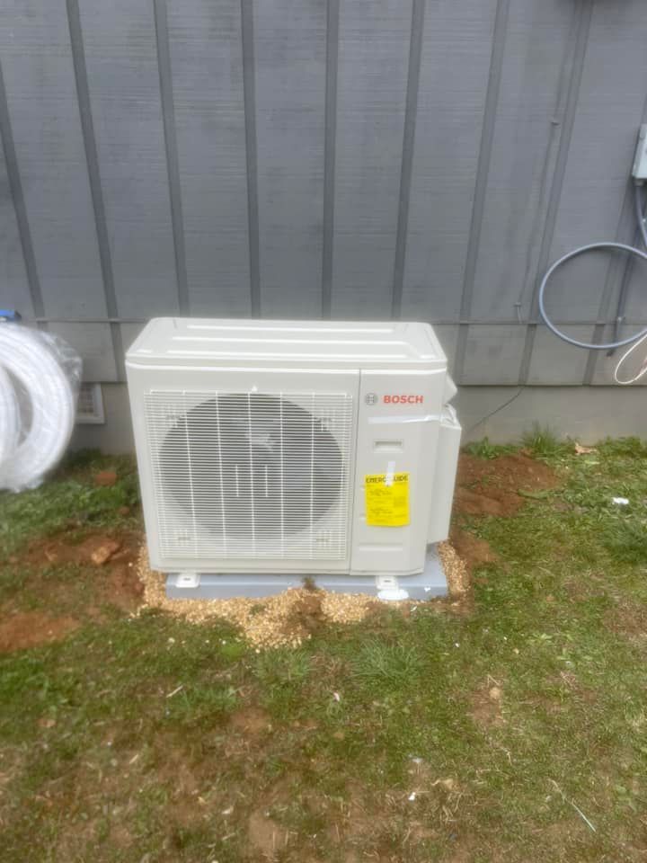 A white air conditioner is sitting in the grass in front of a building.