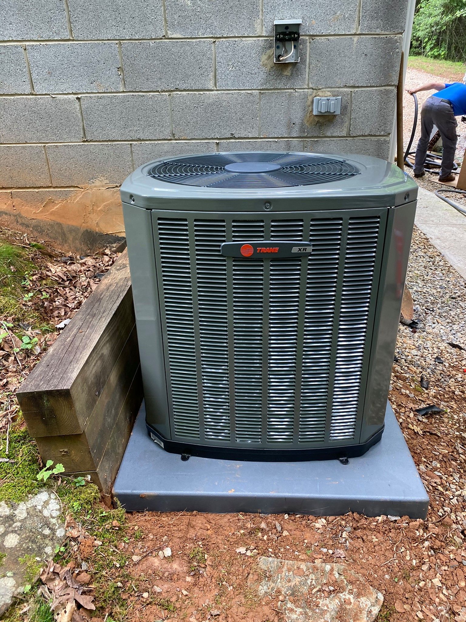 A large air conditioner is sitting outside of a brick building.