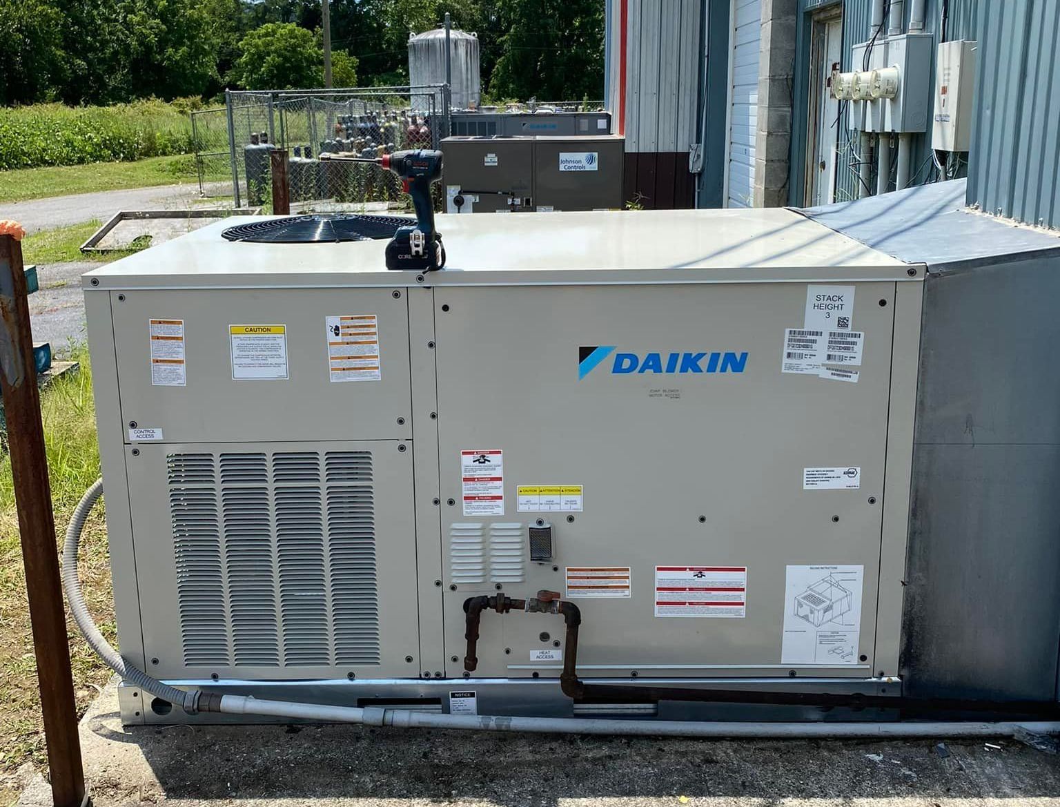 A daikin air conditioner is sitting outside of a building.