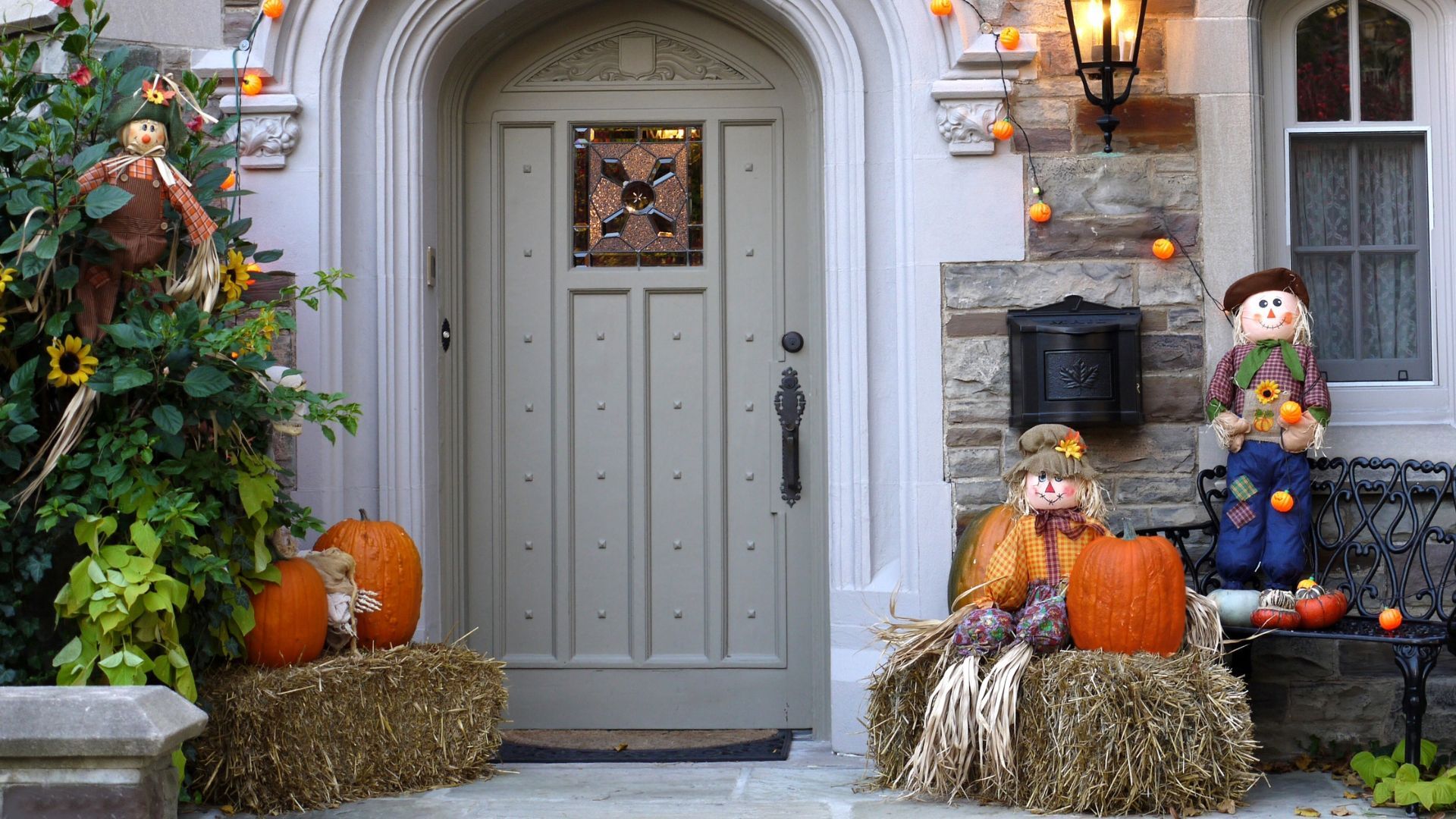 A front door decorated for halloween with pumpkins and hay bales