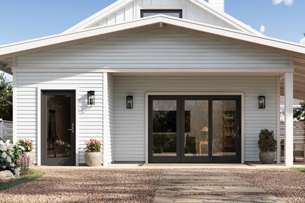 A white house with black windows and a wooden walkway leading to it.