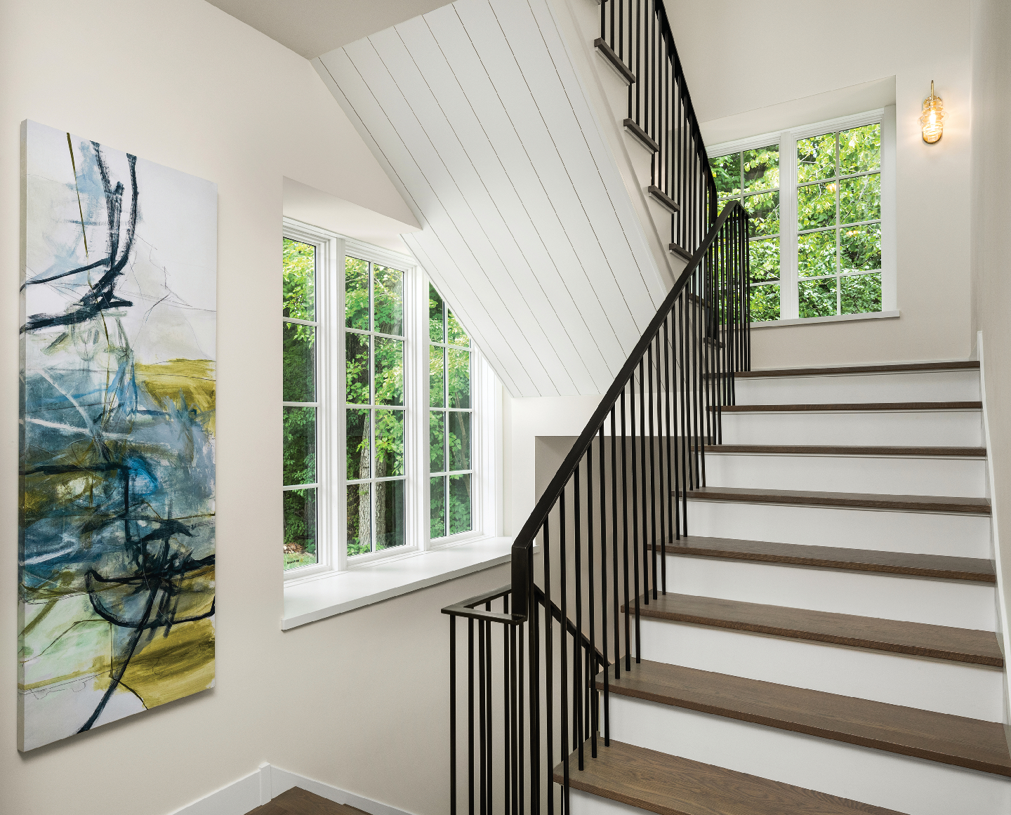 A staircase with a black railing and a painting on the wall.