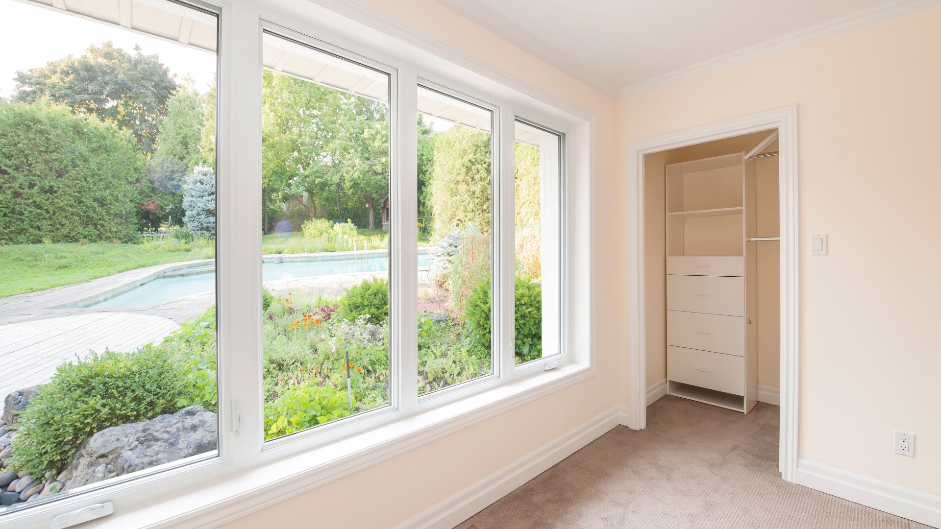 An empty room with a large window and a walk in closet.