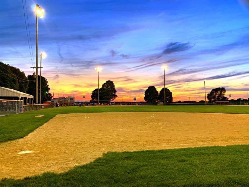 Baseball player sliding into home plate, catcher in front. Blue and gold uniforms, action shot.