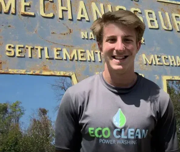 eco clean power washing employ standing in front of a sign that reads Mechanicsburg 