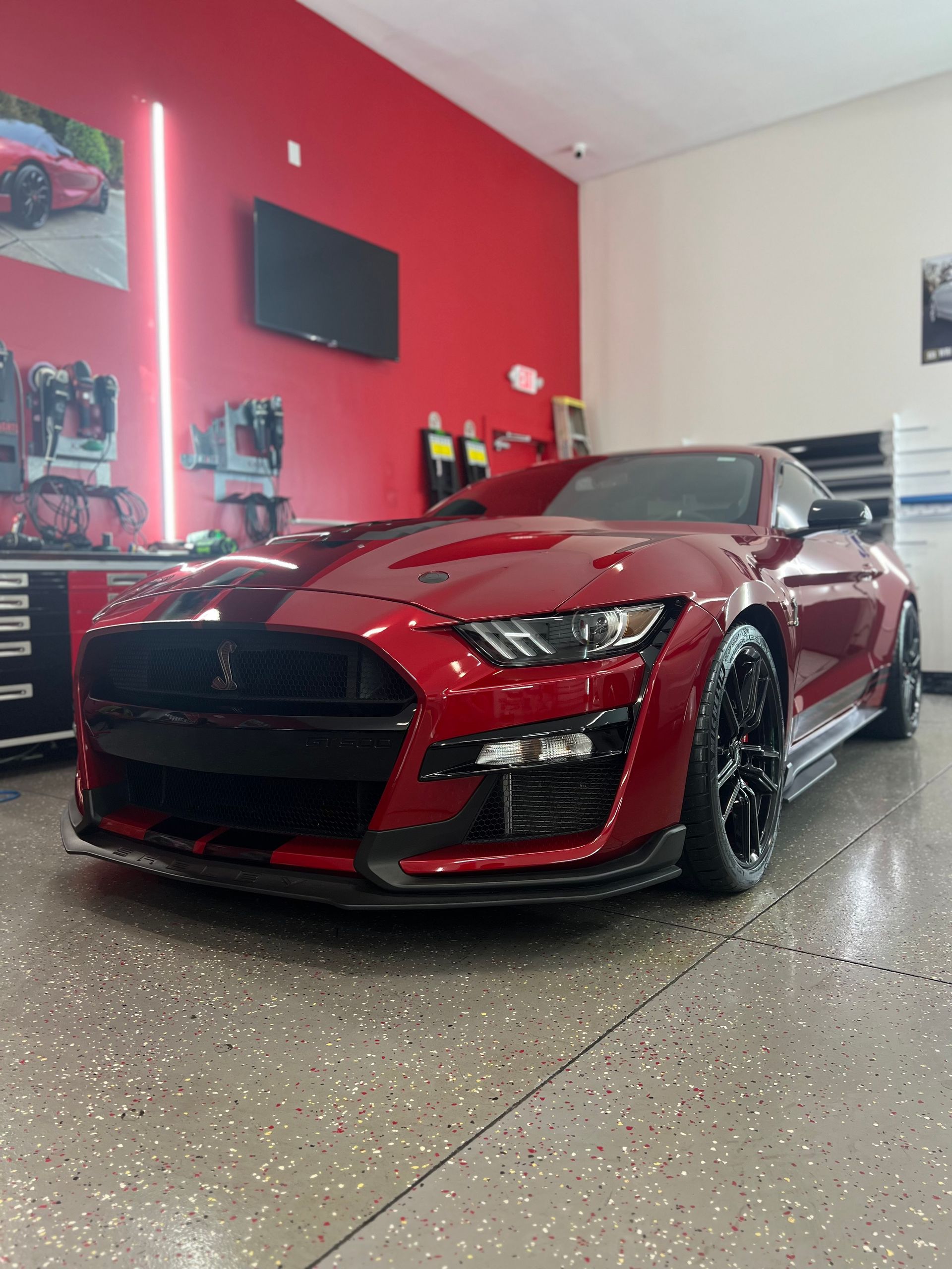 Black SUV in a well-lit garage, parked on a gray floor, with reflective surfaces.