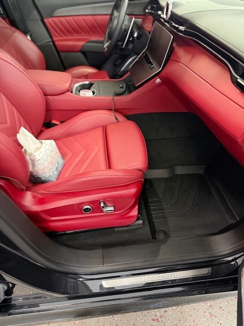Red leather car interior with black floor mats.
