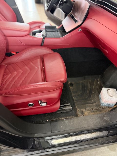 Red leather car interior with dirty floor mat and tissue box.