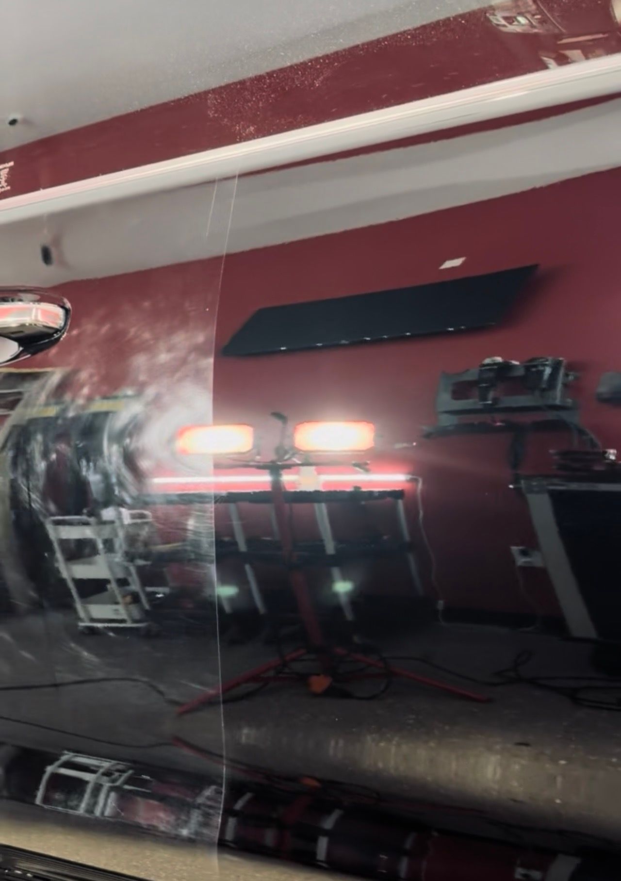 Reflection of a red-walled room with equipment and lights, seen through a transparent surface.