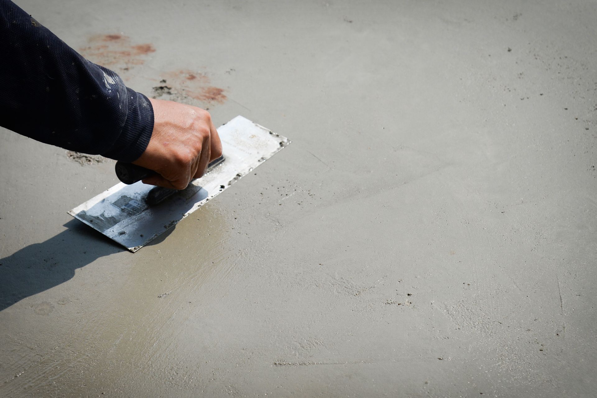 Hand smoothing wet concrete with a trowel outdoors. Hand smoothing wet concrete with a trowel outdoors.