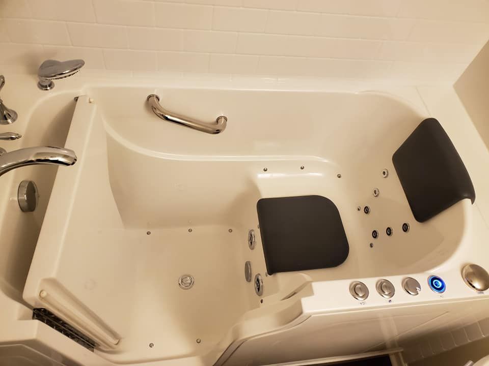 A walk in tub with a black seat and handles