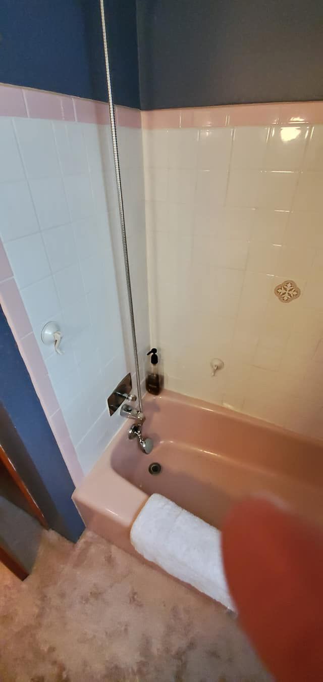 A bathroom with a pink bathtub and a blue wall.