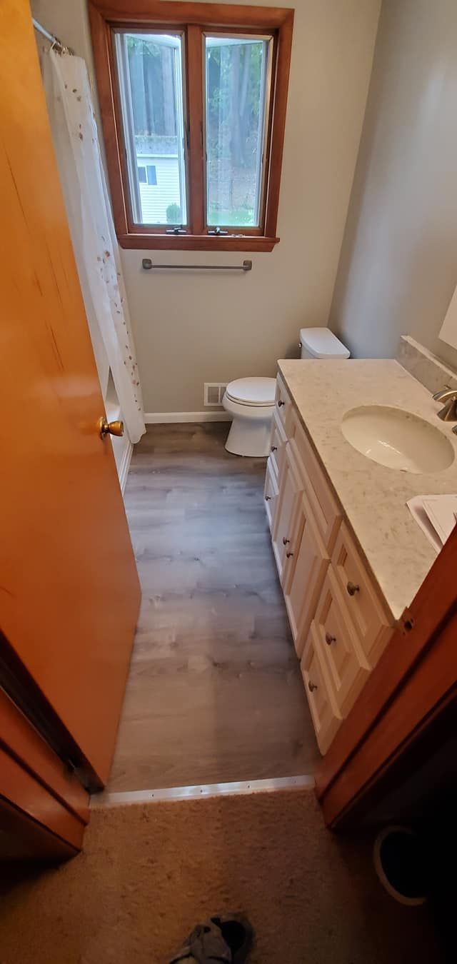 A bathroom with a sink , toilet and window.