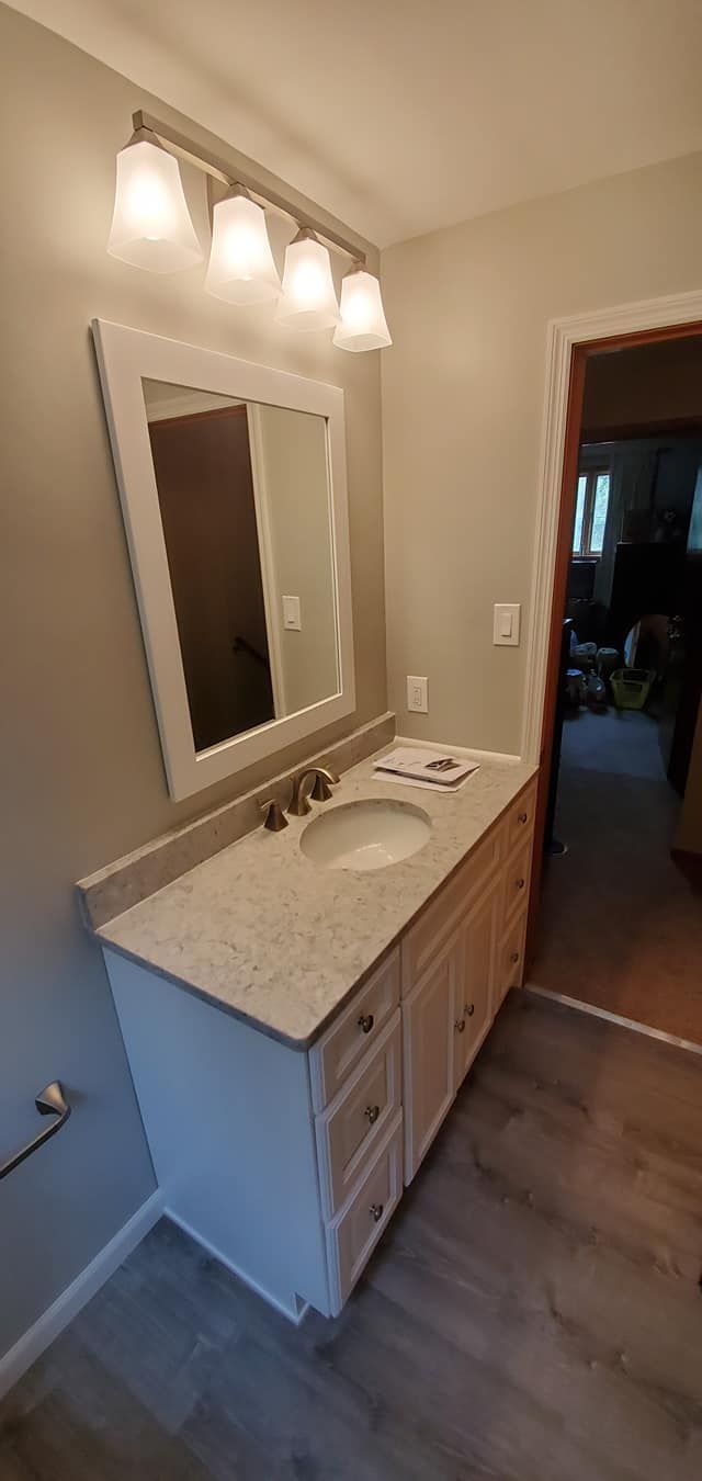 A bathroom with a sink , mirror and light fixture.