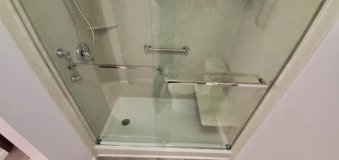 A bathroom with a walk in shower with a glass door.