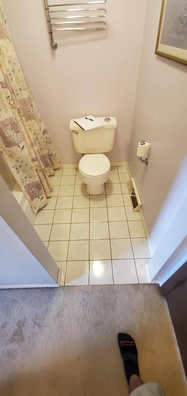 A person is standing in a bathroom next to a toilet.