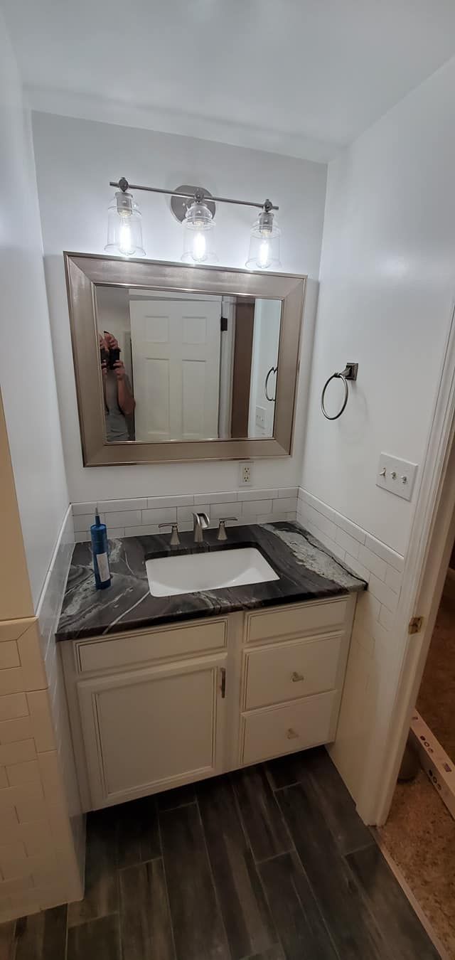 A bathroom with a sink , mirror and cabinets.