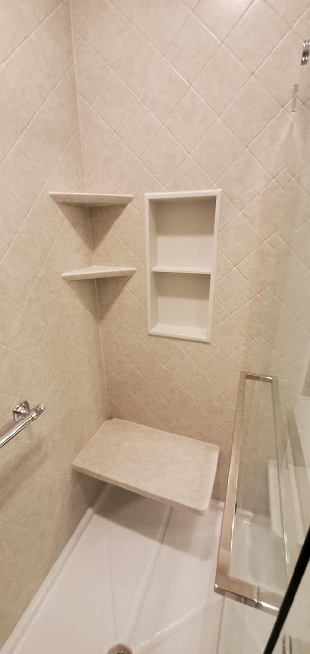 A bathroom with a walk in shower and a bench.