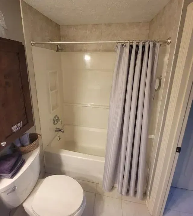 A bathroom with a toilet , bathtub and shower curtain.