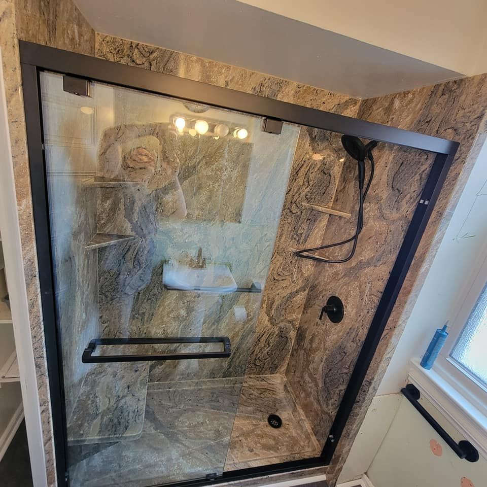 A bathroom with a glass shower door and marble walls.