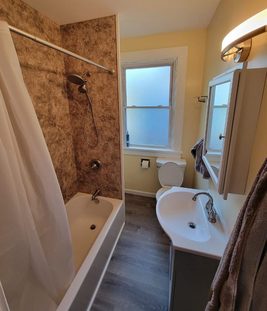 A bathroom with a toilet , tub and shower.