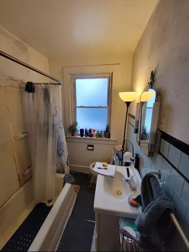 A bathroom with a sink , toilet , shower curtain and mirror.
