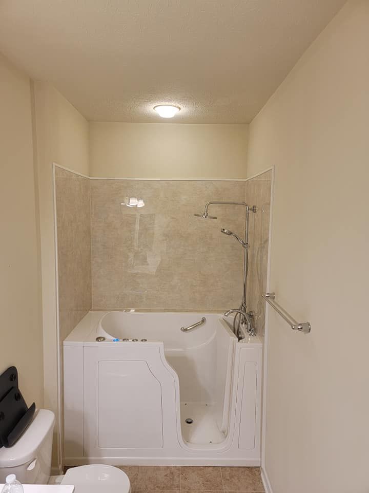 Small bathroom with walk-in tub and shower, beige tile walls, toilet, and grab bar.