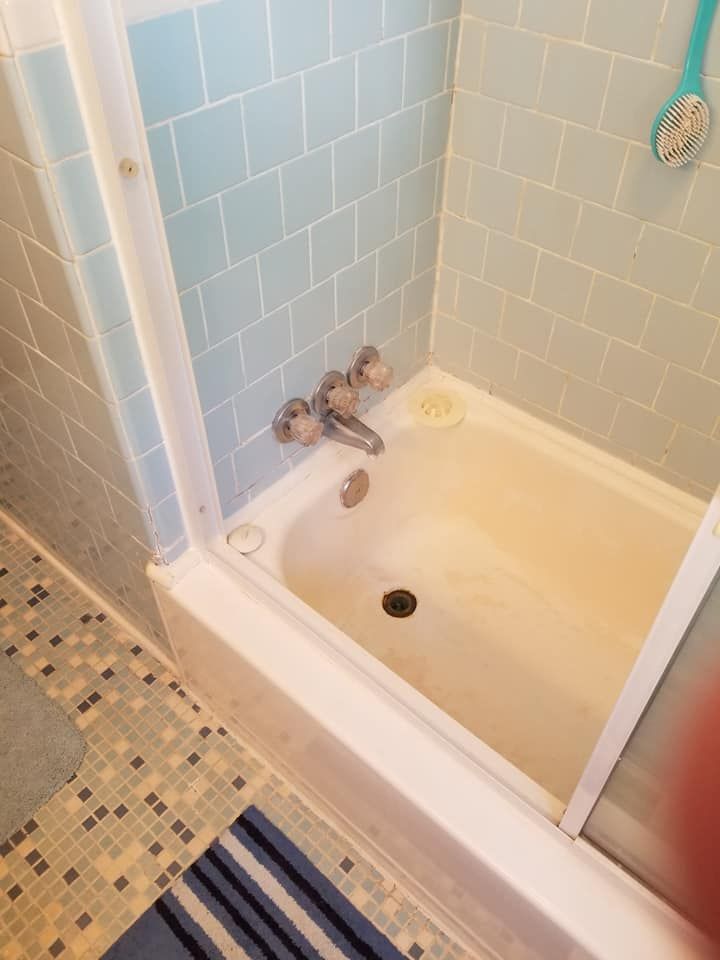 A bathtub in a bathroom with blue tiles and a shower stall.