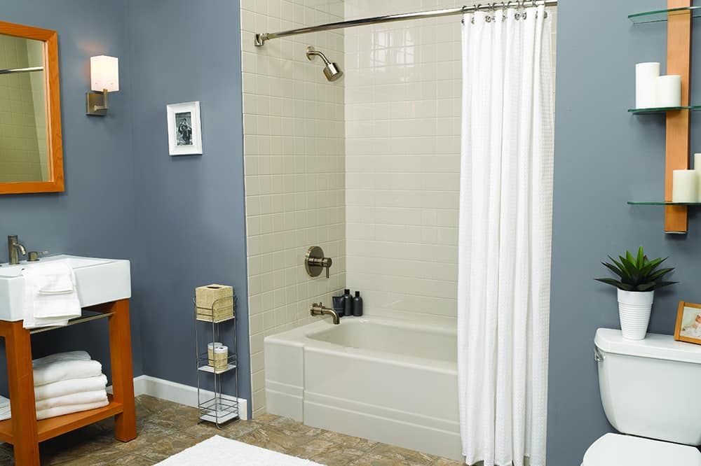 A bathroom with a tub , toilet , sink and mirror