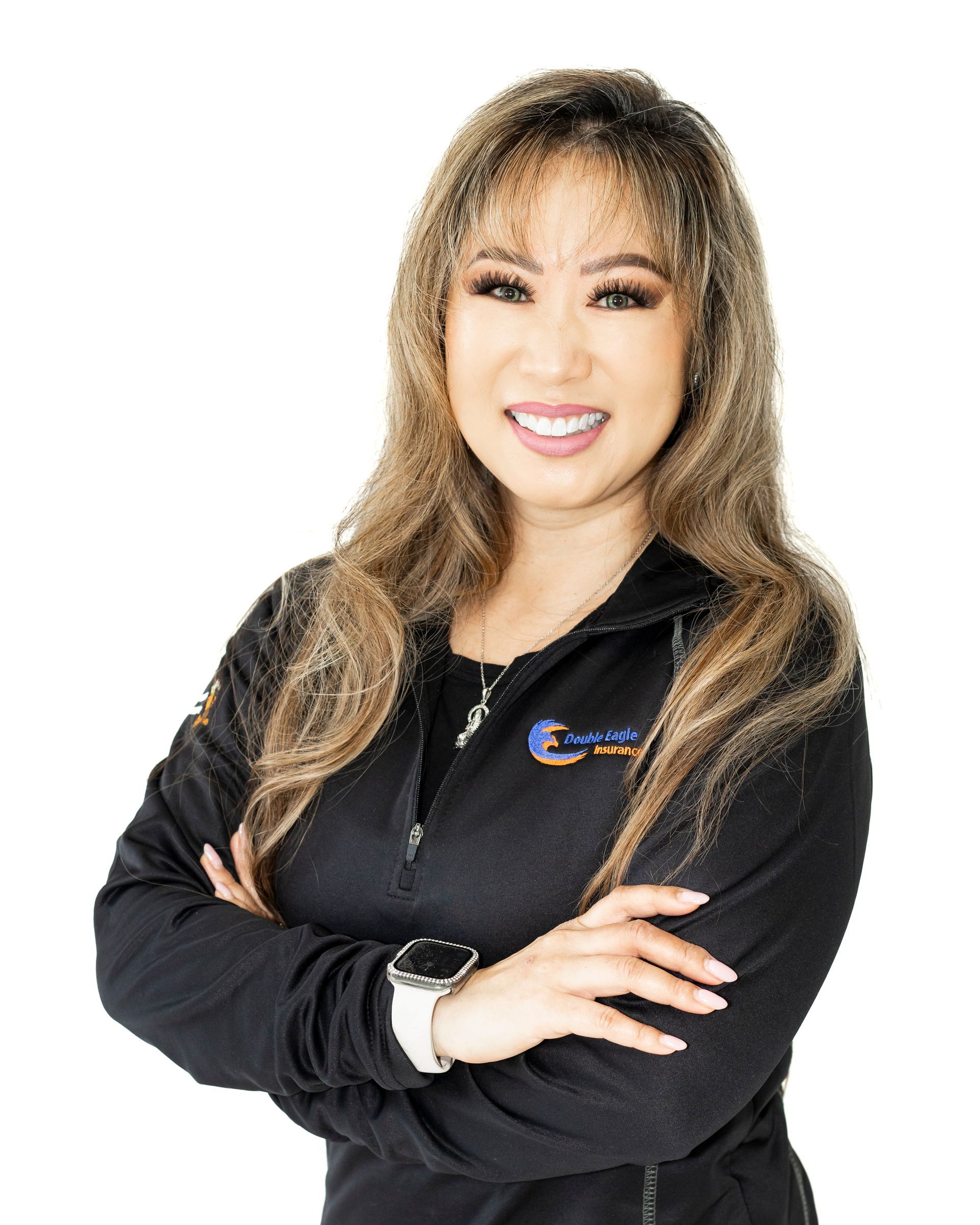 A woman in a black jacket is standing with her arms crossed and smiling.