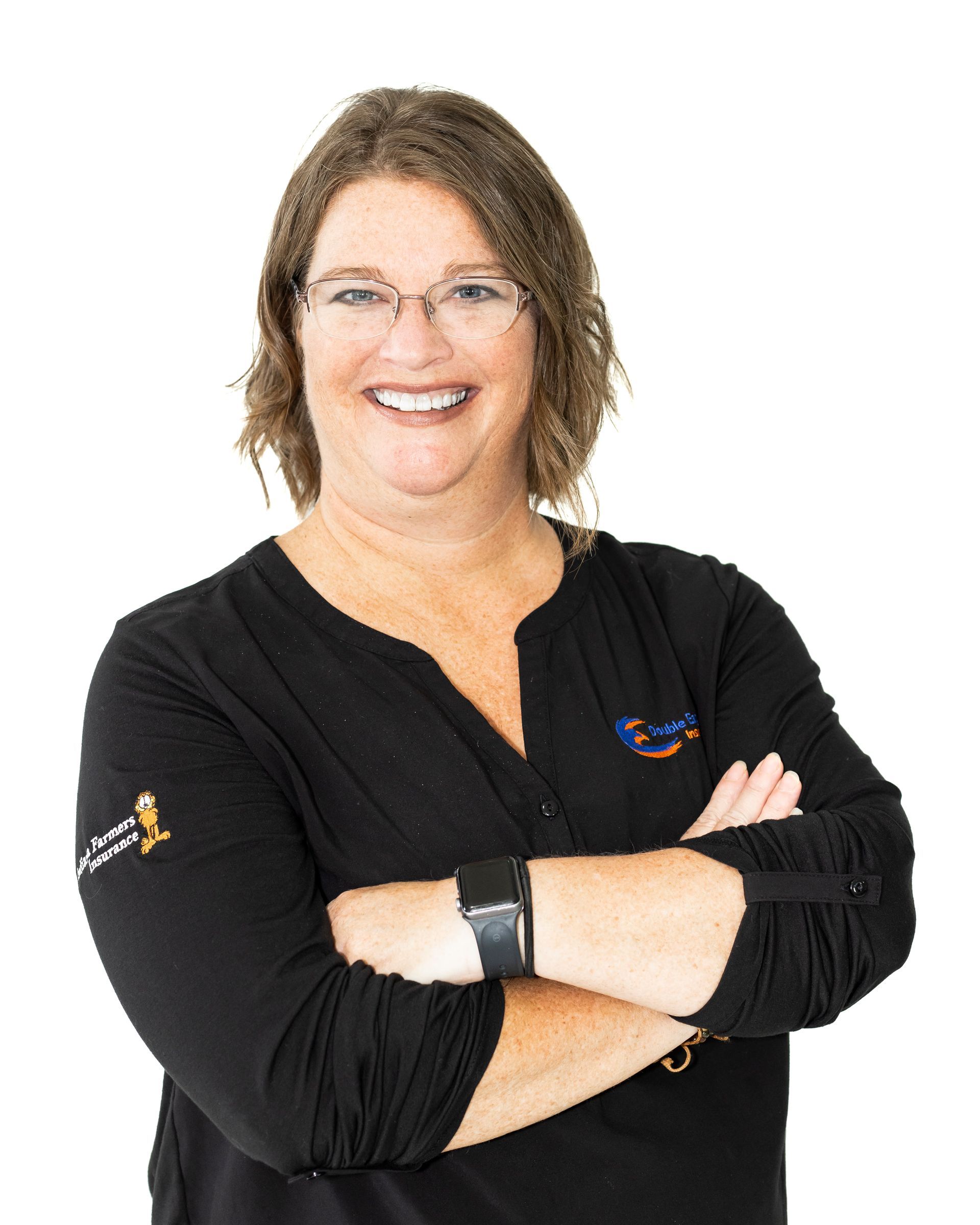 A woman wearing glasses and a black shirt is smiling with her arms crossed.