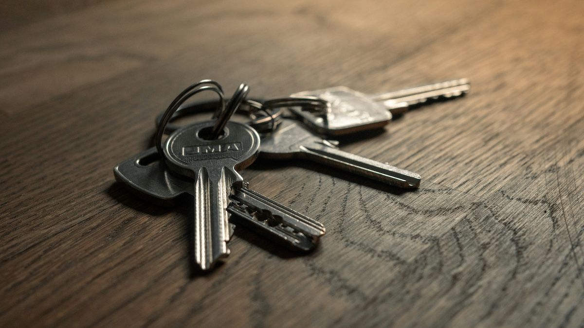 A set of metal keys on a keyring resting on a wooden surface.