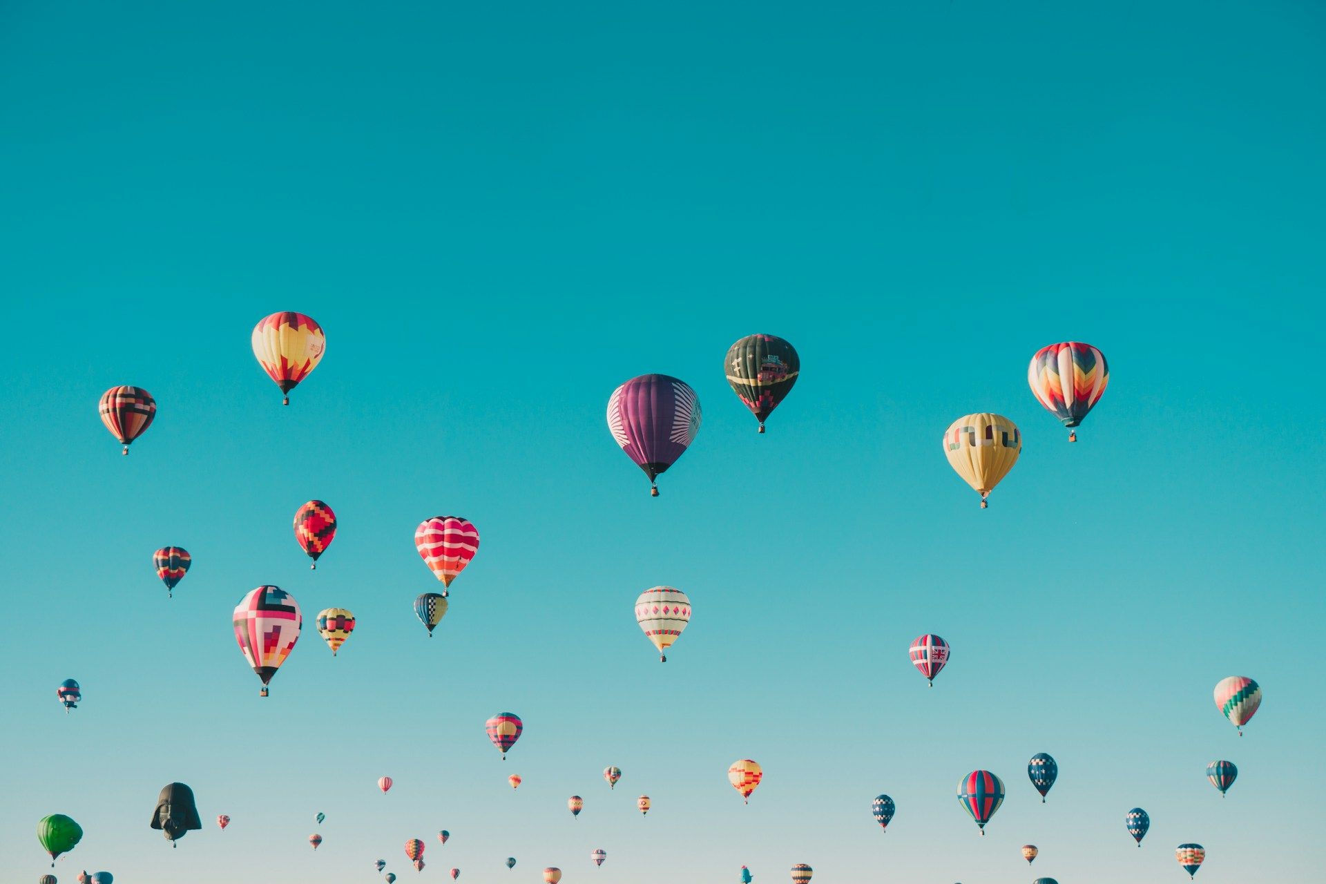 Colorful hot air balloons against a bright blue sky.