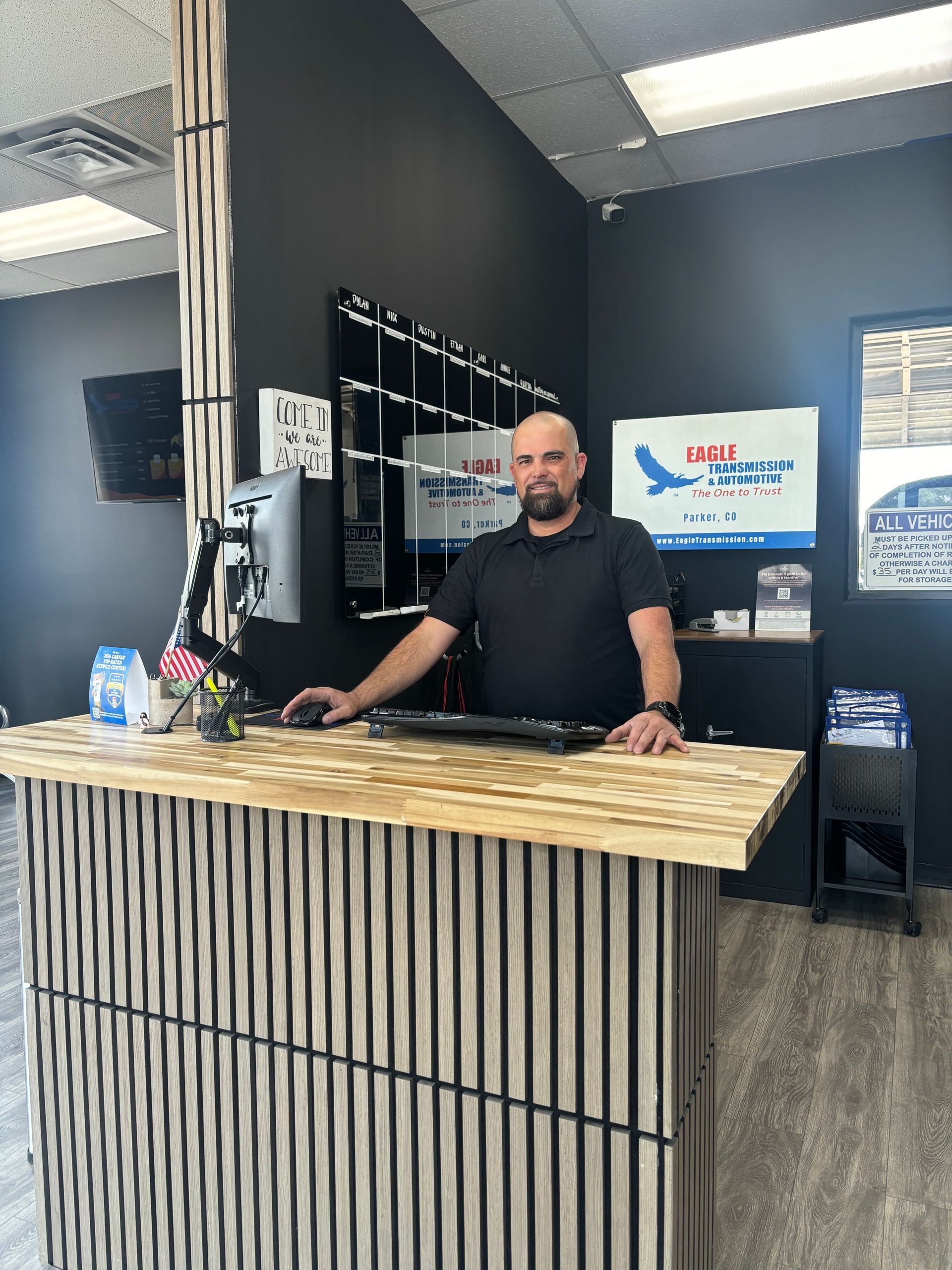 Man at a reception desk with a computer, logo for 