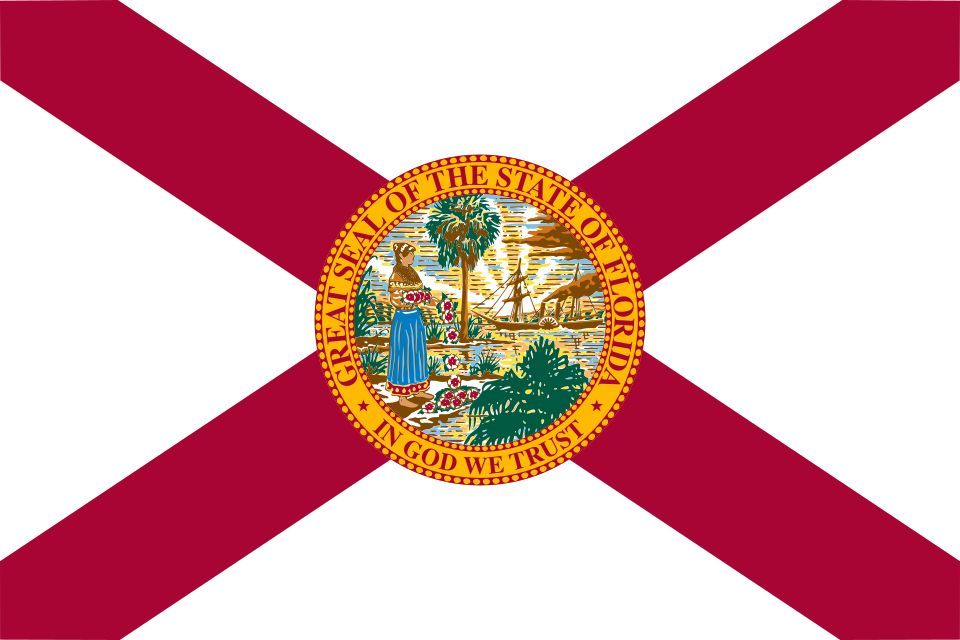 Flag of Florida: a red diagonal cross (saltire) on a white field with the Florida state seal centered, depicting a Seminole woman, a steamboat, and a sabal palm.
