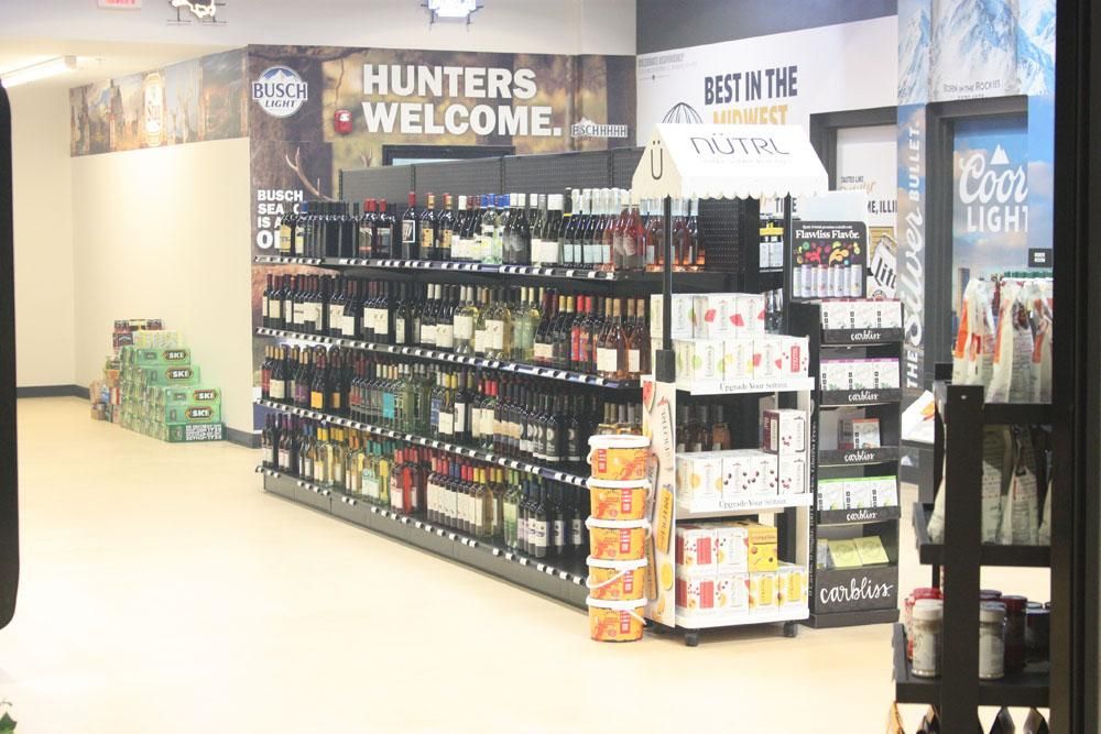 Liquor store interior with shelves stocked with wine, cases of beverages, and a 