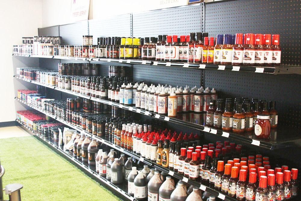 Multiple shelves lined with rows of assorted bottles of hot sauce and condiments in a store.