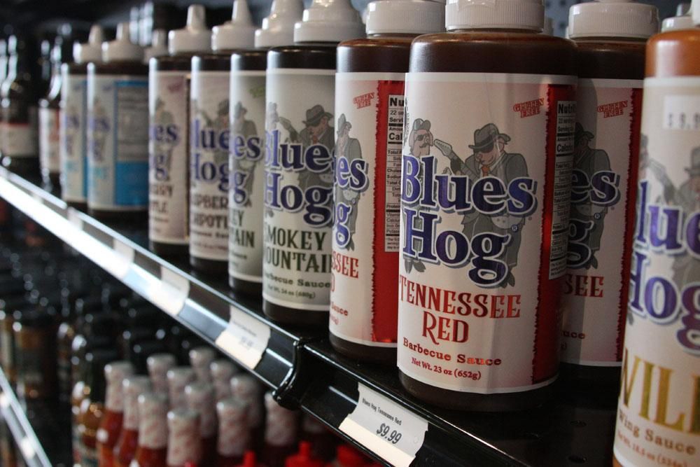 Rows of Blues Hog brand barbecue sauce bottles lined up on a grocery store shelf.